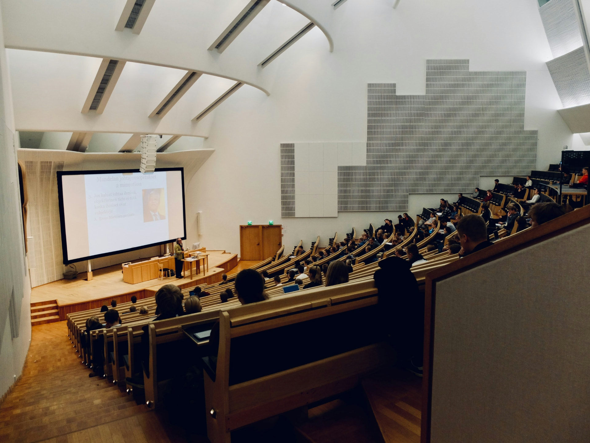 Students attending a lecture in a large modern university auditorium
